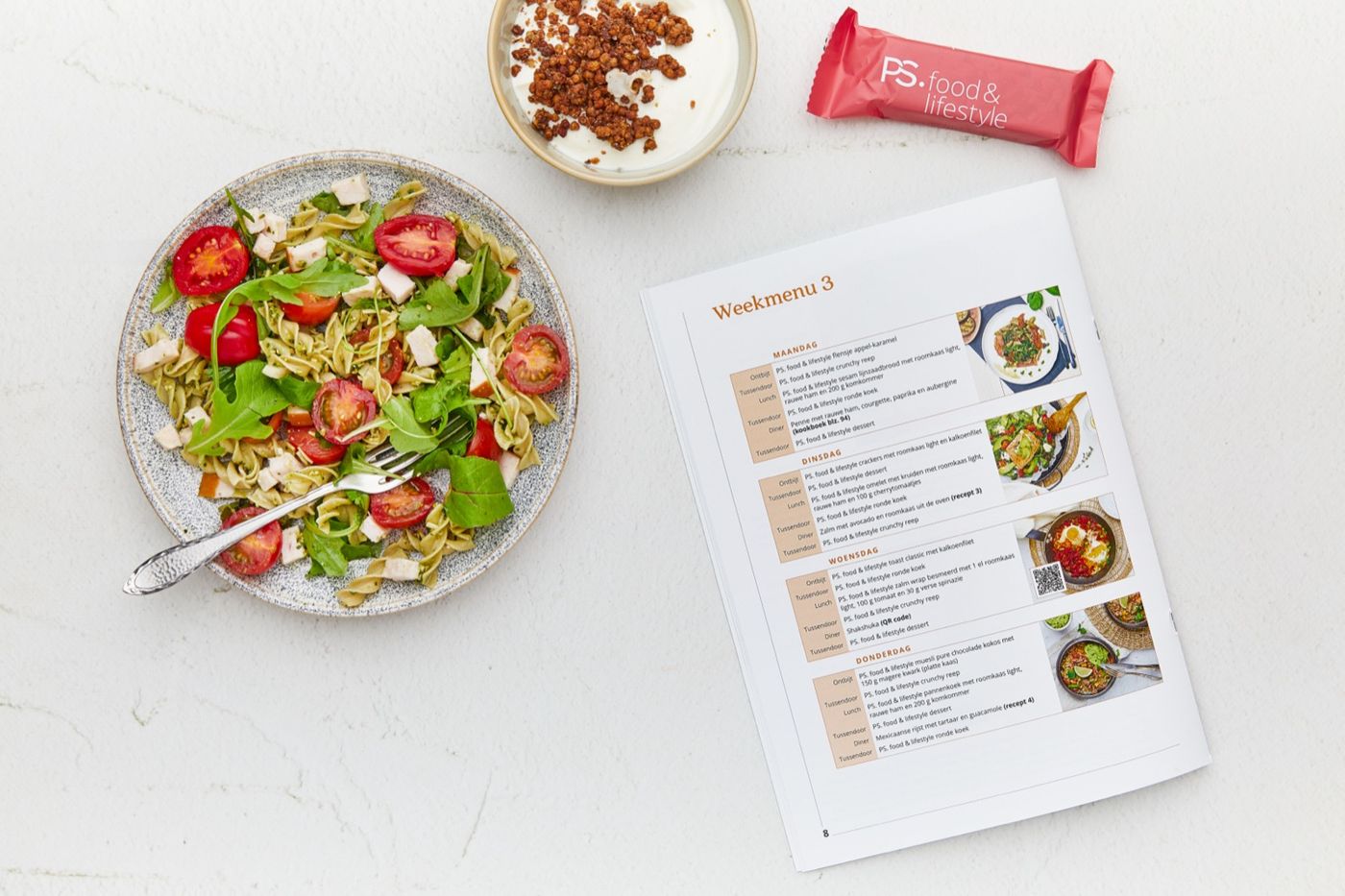 Een dagmenu met pastasalade, yoghurt met fruit en een PS. food & lifestyle reep